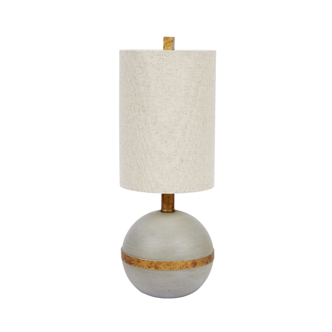 Modern table lamp with cylindrical linen shade and round sculpted base featuring gold accent band on white background