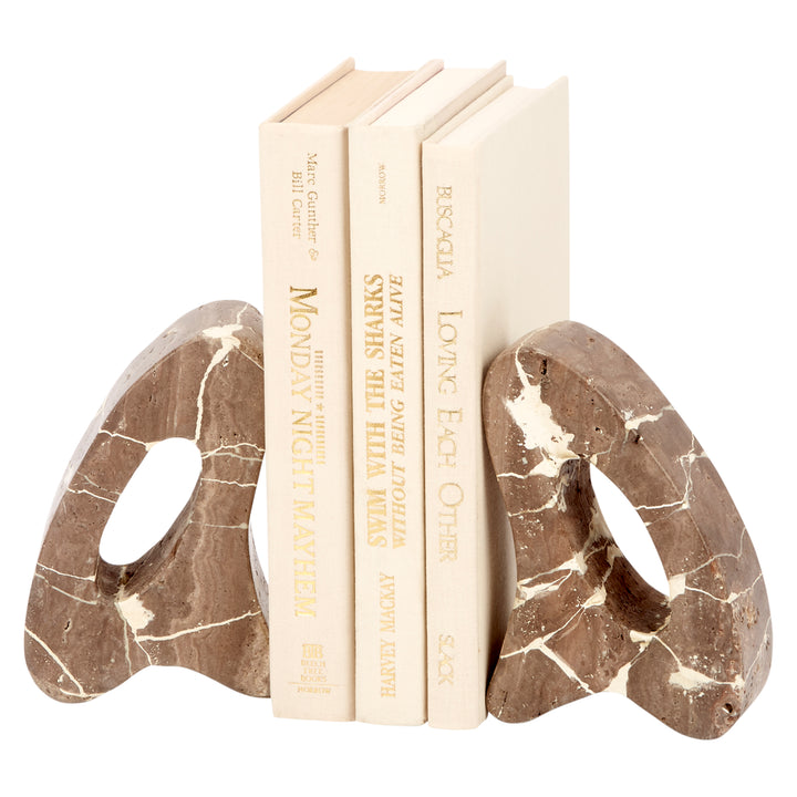 Decorative beige travertine bookends with oval cutout, holding upright books