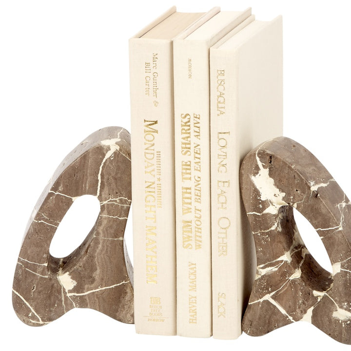 Decorative beige travertine bookends with arched oval cutouts, holding upright books