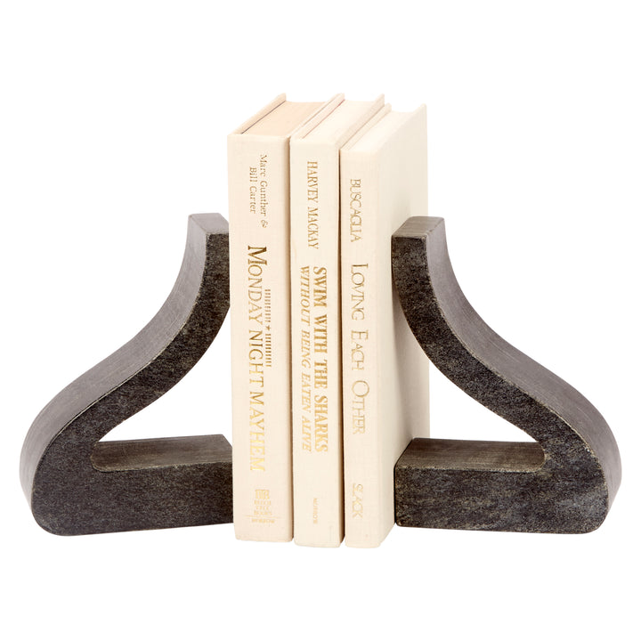 Black marble bookends with ornate curved cutouts, holding stacked cream books
