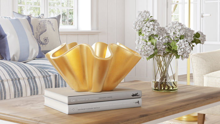 Gold metallic wave bowl on tabletop, fluted edges and hollow center