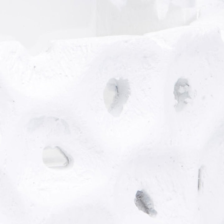 White gesso candleholder detail with irregular cutout holes on side