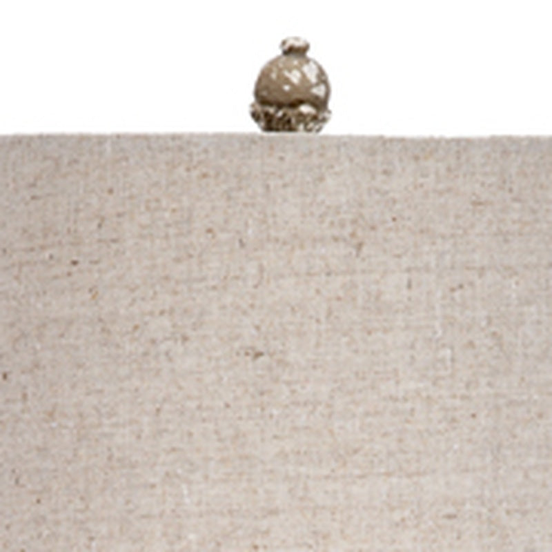 Gray linen lamp shade with top finial on aged glass base