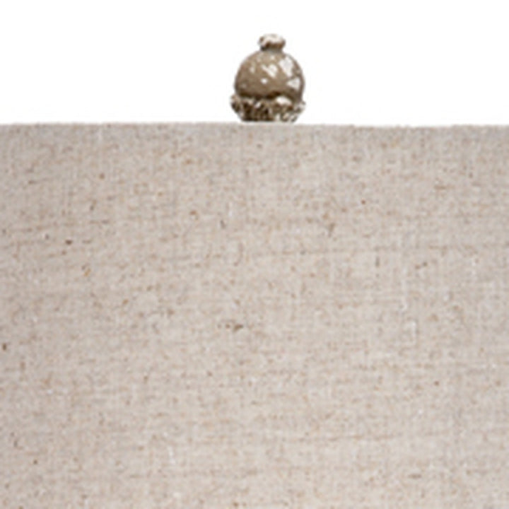 Gray linen lamp shade with top finial on aged glass base