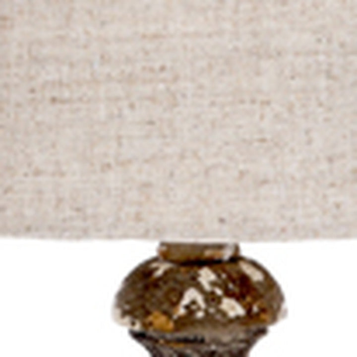 Aged gold glass lamp base top beneath gray linen shade