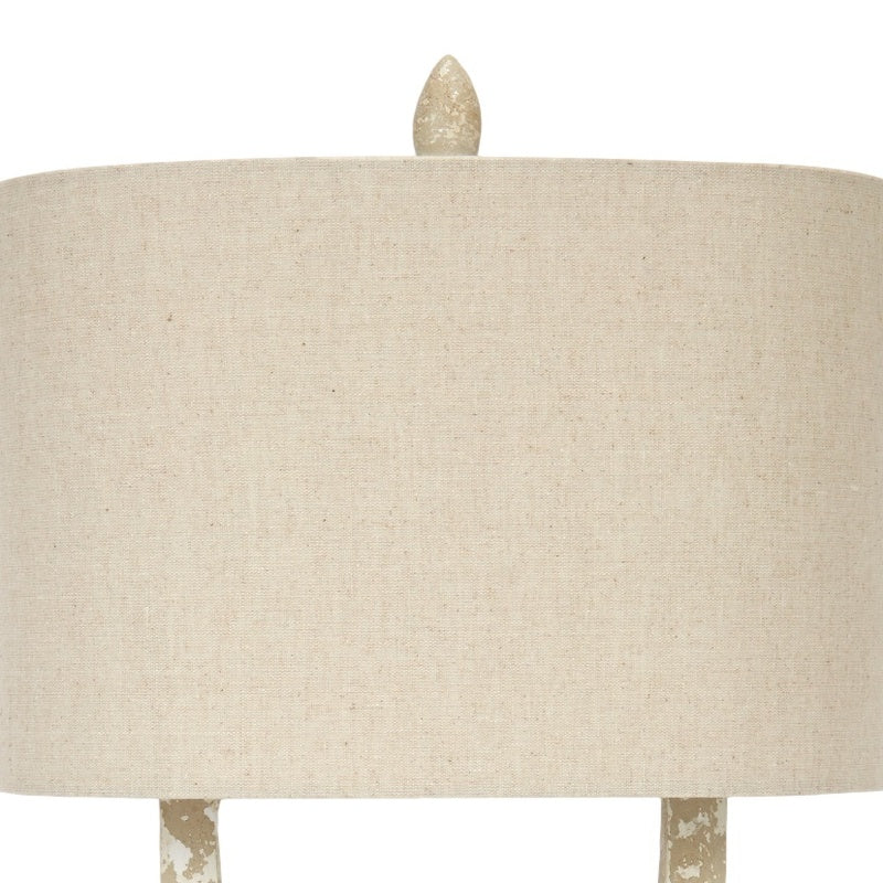 Off-white fabric lamp shade on a distressed white and gold lamp base