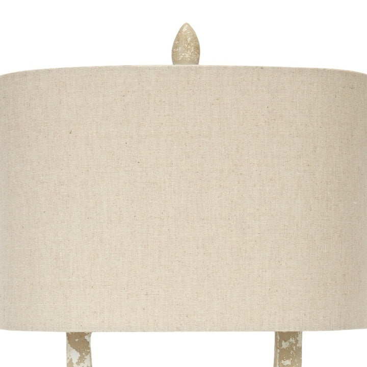 Off-white fabric lamp shade on a distressed white and gold lamp base