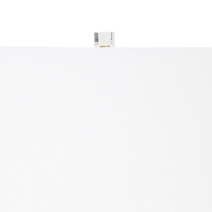 Table lamp top with white shade, brass finial, and clear center pole