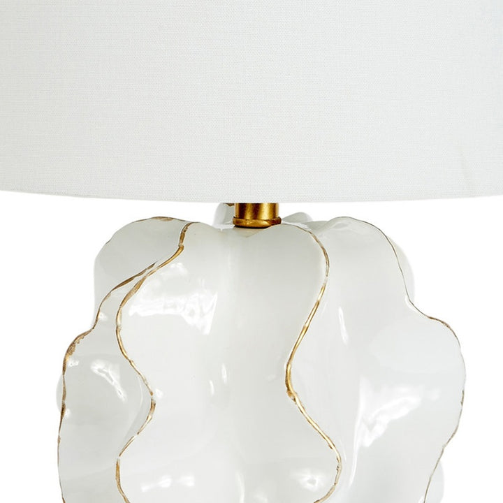 White ceramic lamp base with flowing gold accents under white linen shade