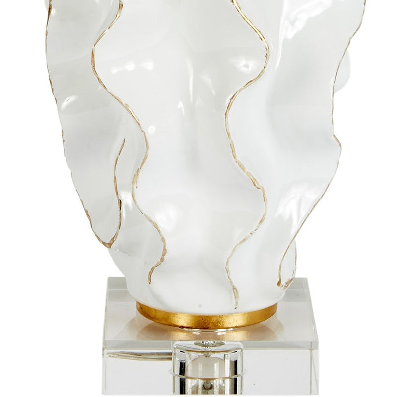 White ceramic lamp base on clear acrylic pedestal with gold trim and linen shade