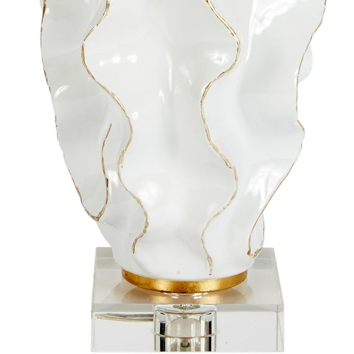 White ceramic lamp base on clear acrylic pedestal with gold trim and linen shade