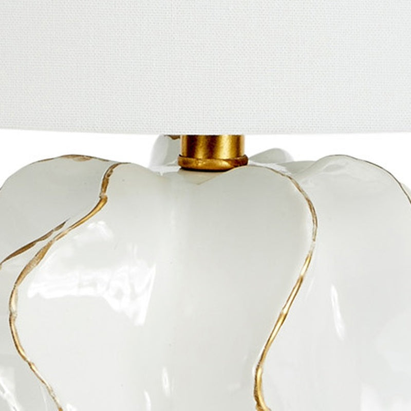 White ceramic lamp top with gold accents under white linen shade