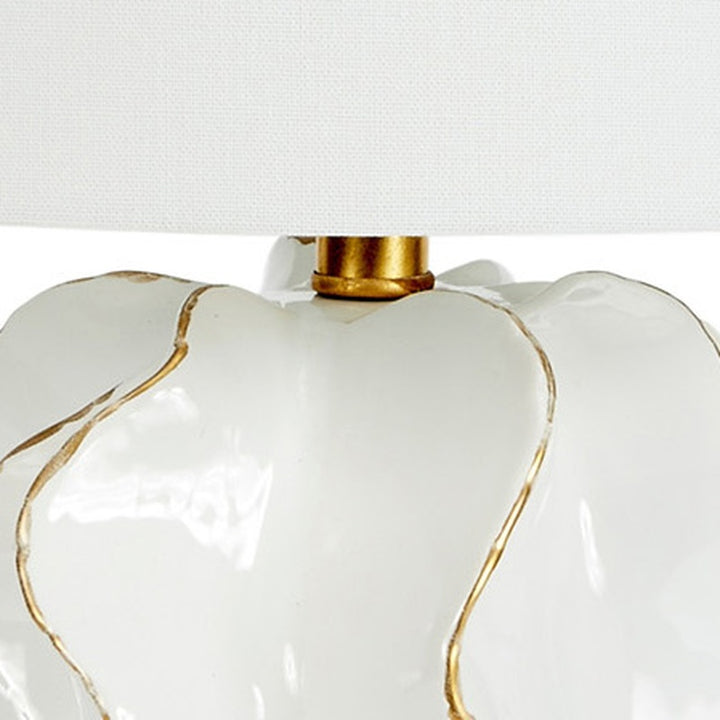White ceramic lamp top with gold accents under white linen shade