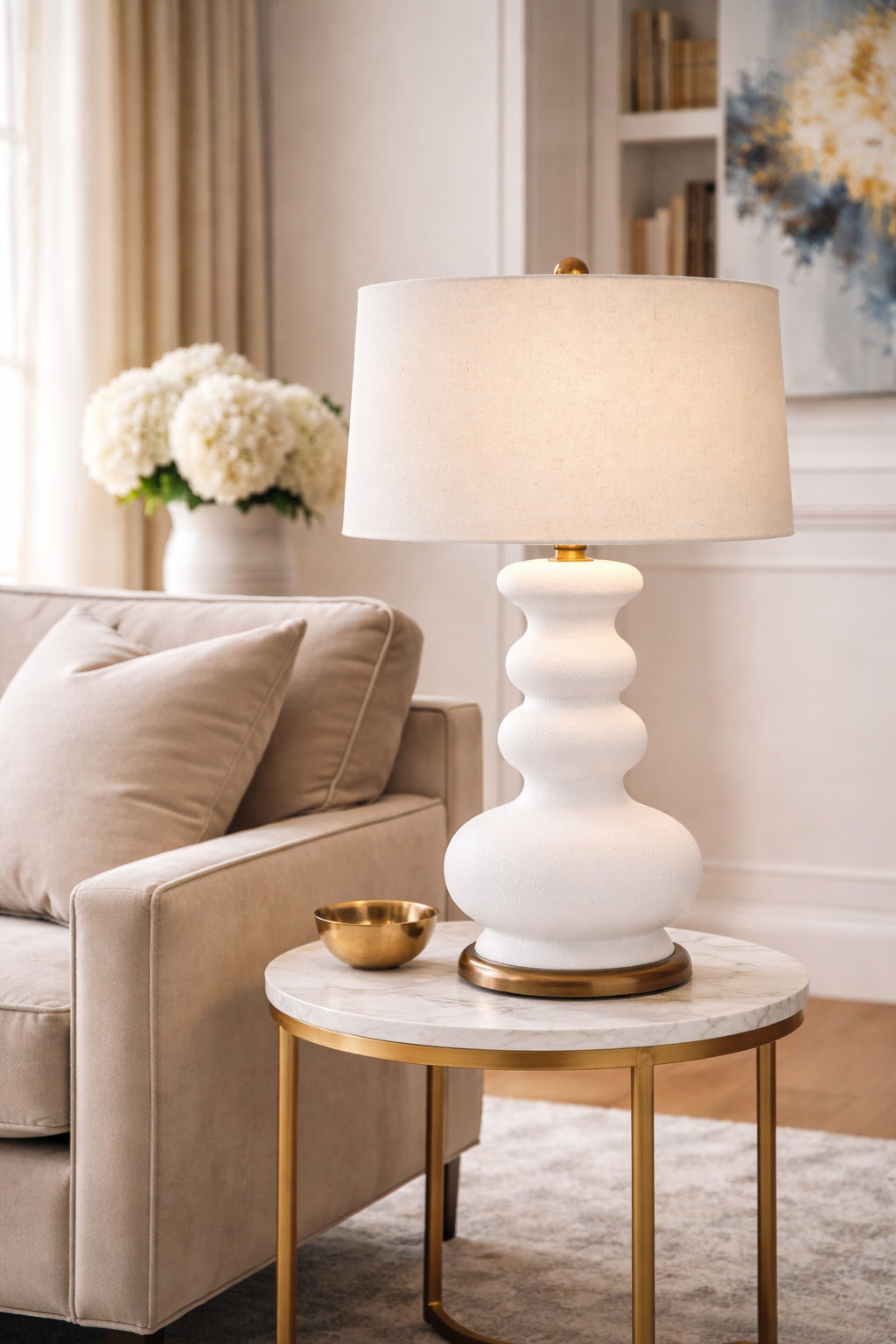 White lamp on a marble side table in a living room setting with beige sofa and decorative items.