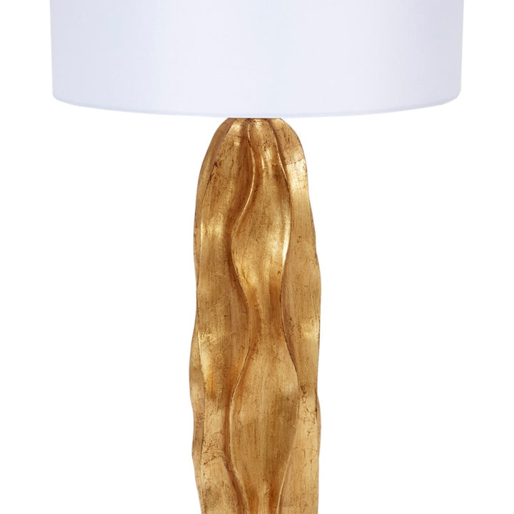 Gold leaf table lamp with white drum shade, close view of gold sculpted base