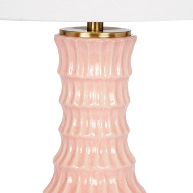 Blush ceramic lamp body with gold top hardware and white drum shade, close-up