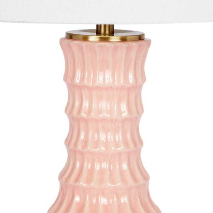Blush ceramic lamp body with gold top hardware and white drum shade, close-up