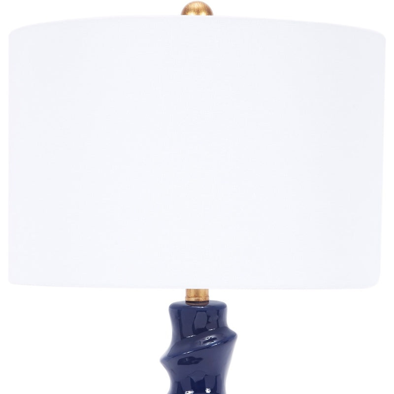 Table lamp with white drum shade and navy ceramic base with gold-toned neck