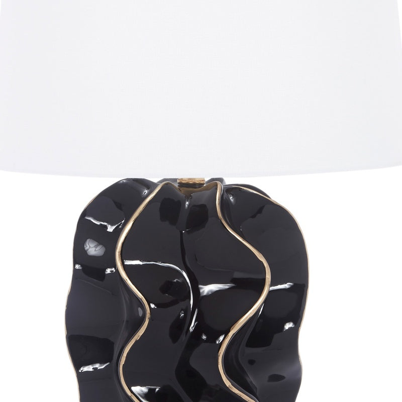 Glossy black ceramic wave lamp base with gold edge accents and white fabric shade