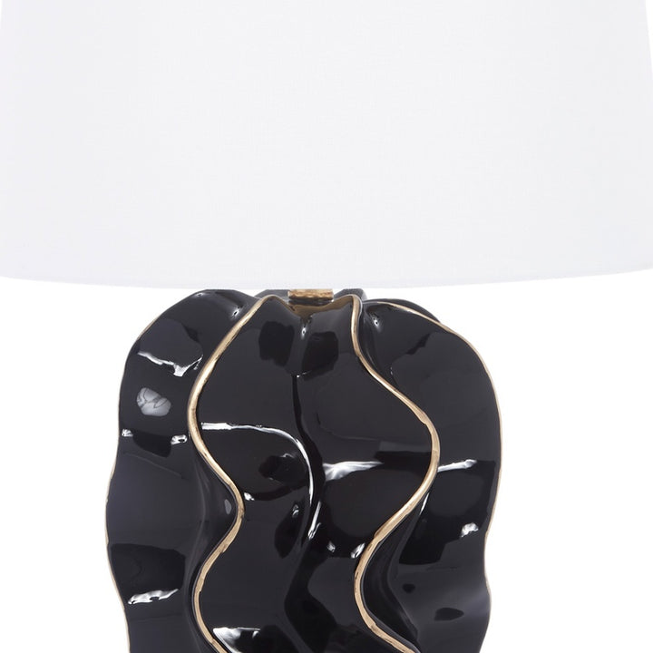 Glossy black ceramic wave lamp base with gold edge accents and white fabric shade