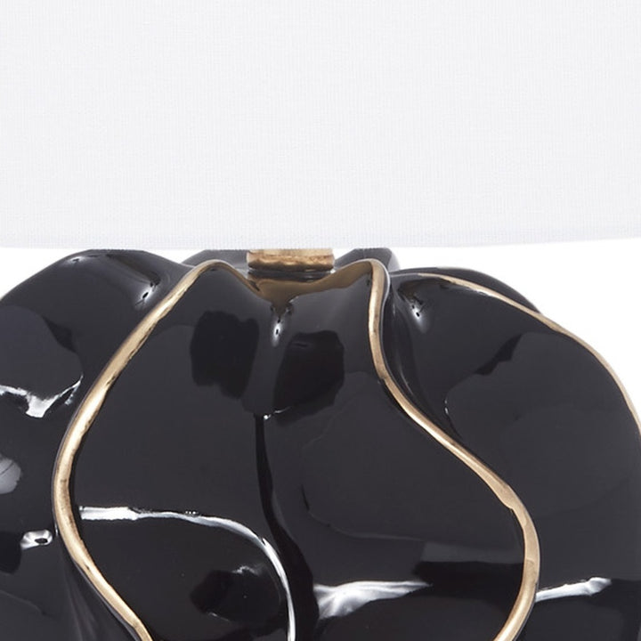 Glossy black ceramic lamp base top with gold accents and white fabric shade