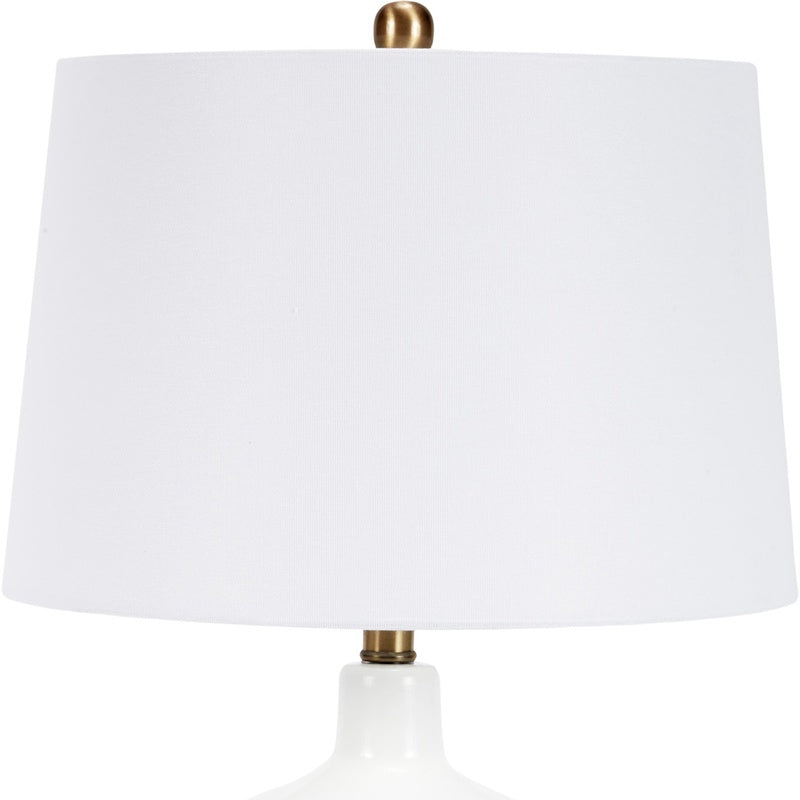 White fabric drum shade on modern glass table lamp with brass base hardware