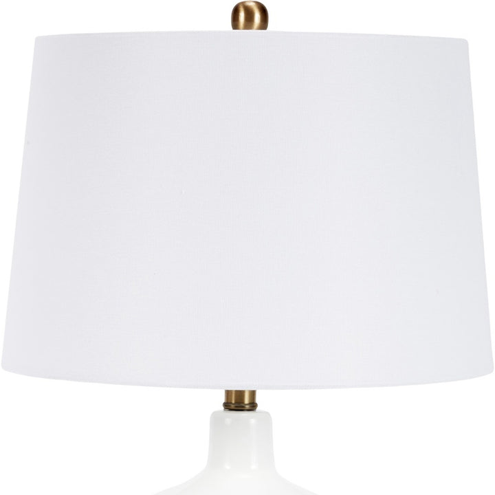 White fabric drum shade on modern glass table lamp with brass base hardware