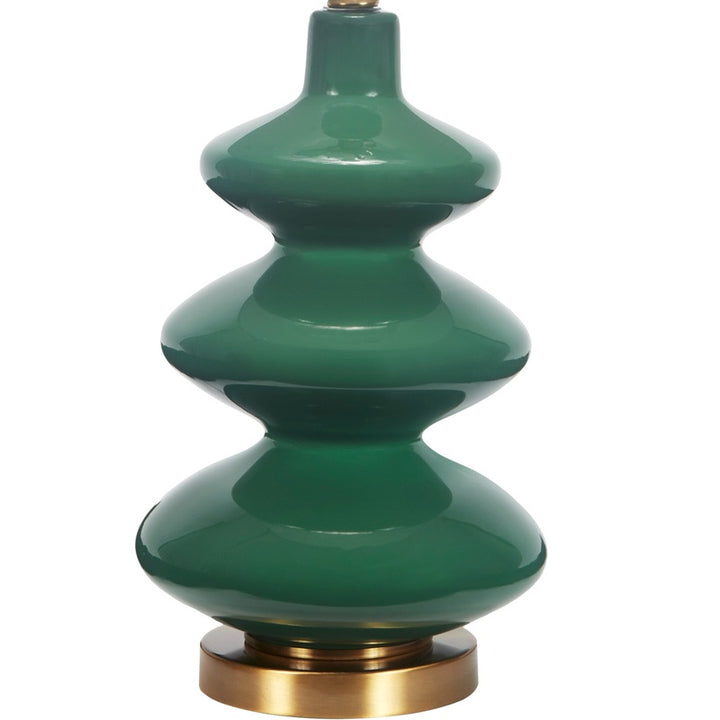 Green glass table lamp with white fabric shade, brass base ring, and stacked body