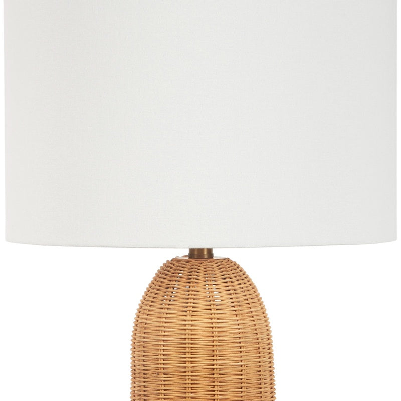 Table lamp with white linen shade and woven rattan base, brass stem visible