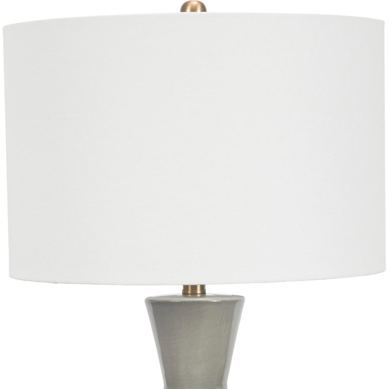 Gray ceramic table lamp with white linen drum shade and brass neck cap