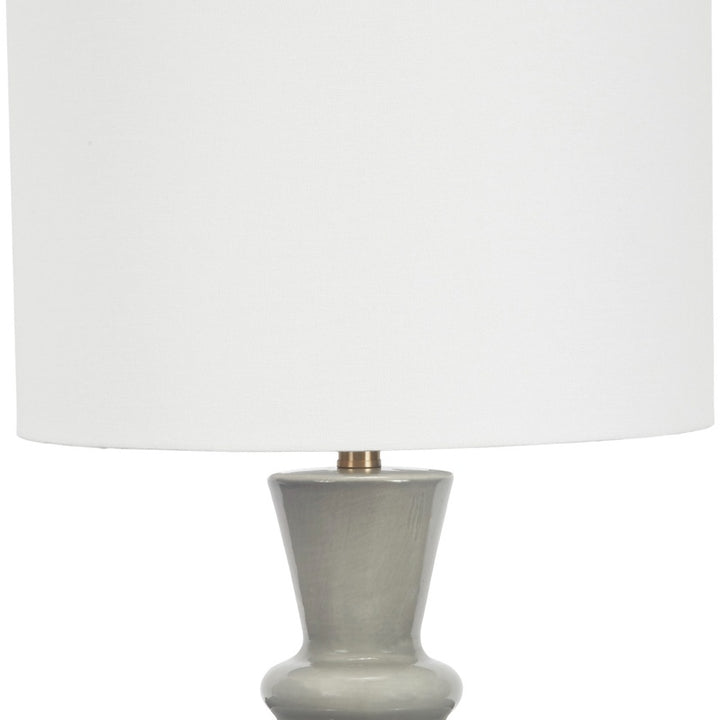 Gray ceramic table lamp with white linen drum shade and flared base