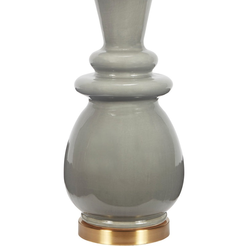Gray ceramic table lamp base with brass foot ring under white linen drum shade
