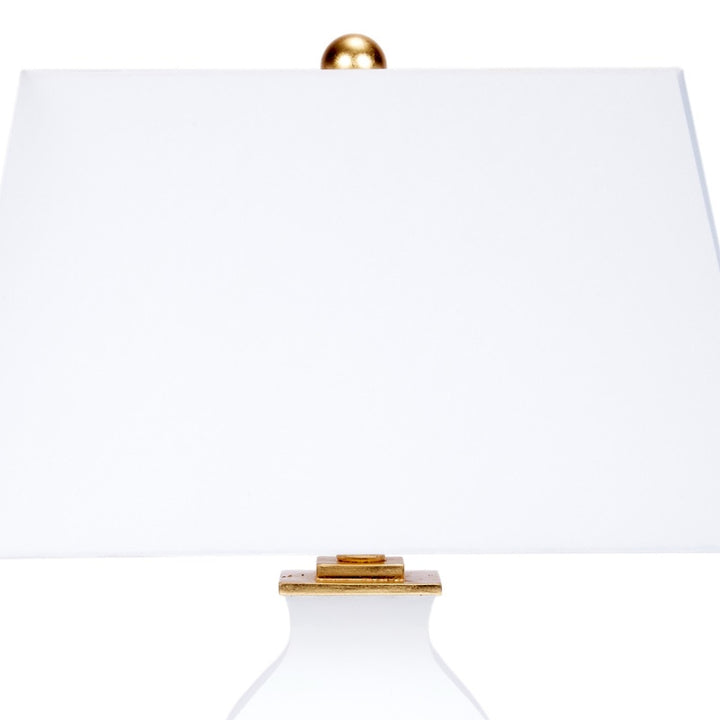 Table lamp with white fabric shade, gold finial, and white glass body with gold collar