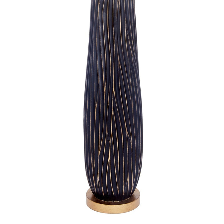 Tall black ribbed lamp base with gold foot ring under drum shade