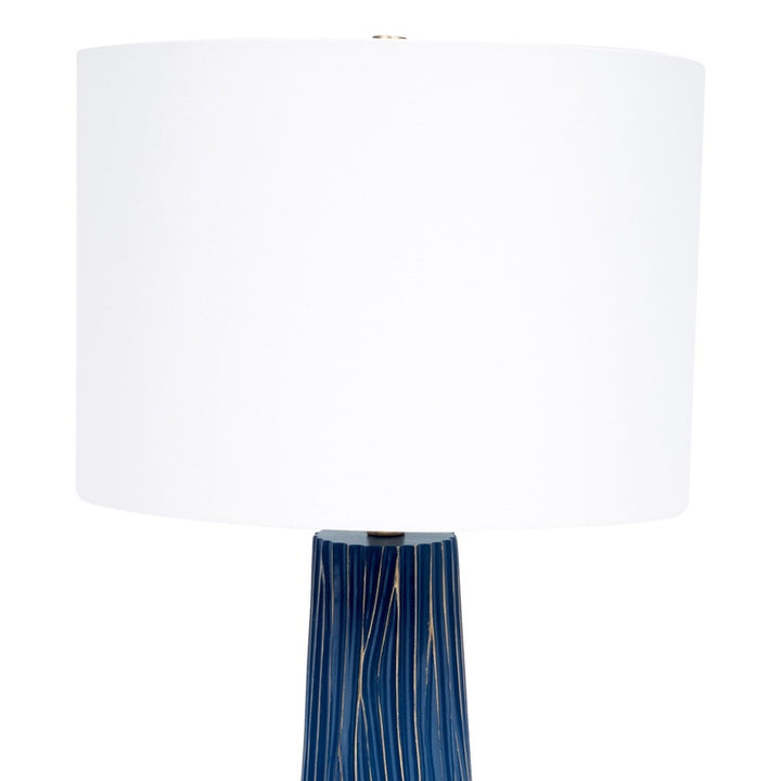 Table lamp with white drum shade and blue ribbed base with gold accents