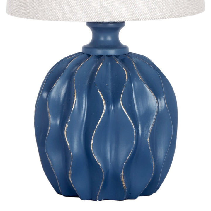 Mini linen lamp shade atop blue ribbed base with textured lines