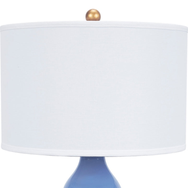 Blue porcelain table lamp with white linen fabric shade and gold finial