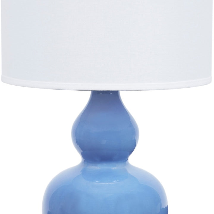 Blue porcelain lamp base with white linen drum shade and gold accents