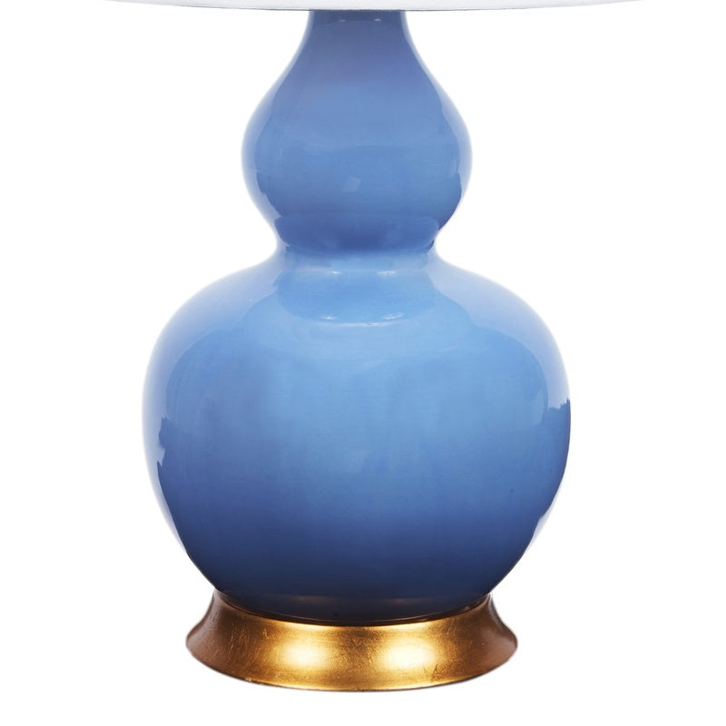 Blue porcelain bulb-style lamp base with white shade and brass bottom trim