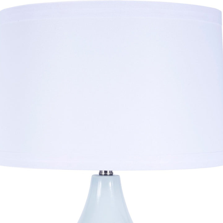 Blue ceramic table lamp with white fabric shade, upper portion