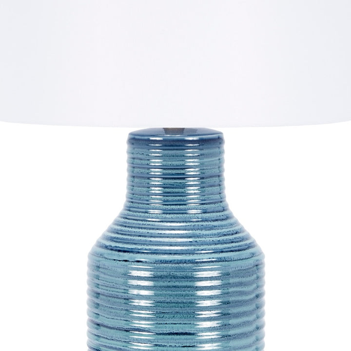 Blue ceramic lamp base under white drum shade, ribbed finish