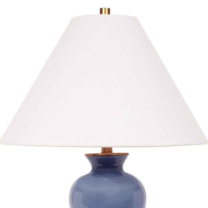 Blue ceramic table lamp with white linen drum shade and brass accents