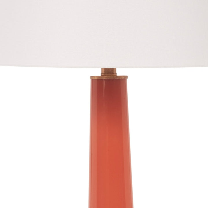 Orange lamp body with brass collar under the white linen shade.