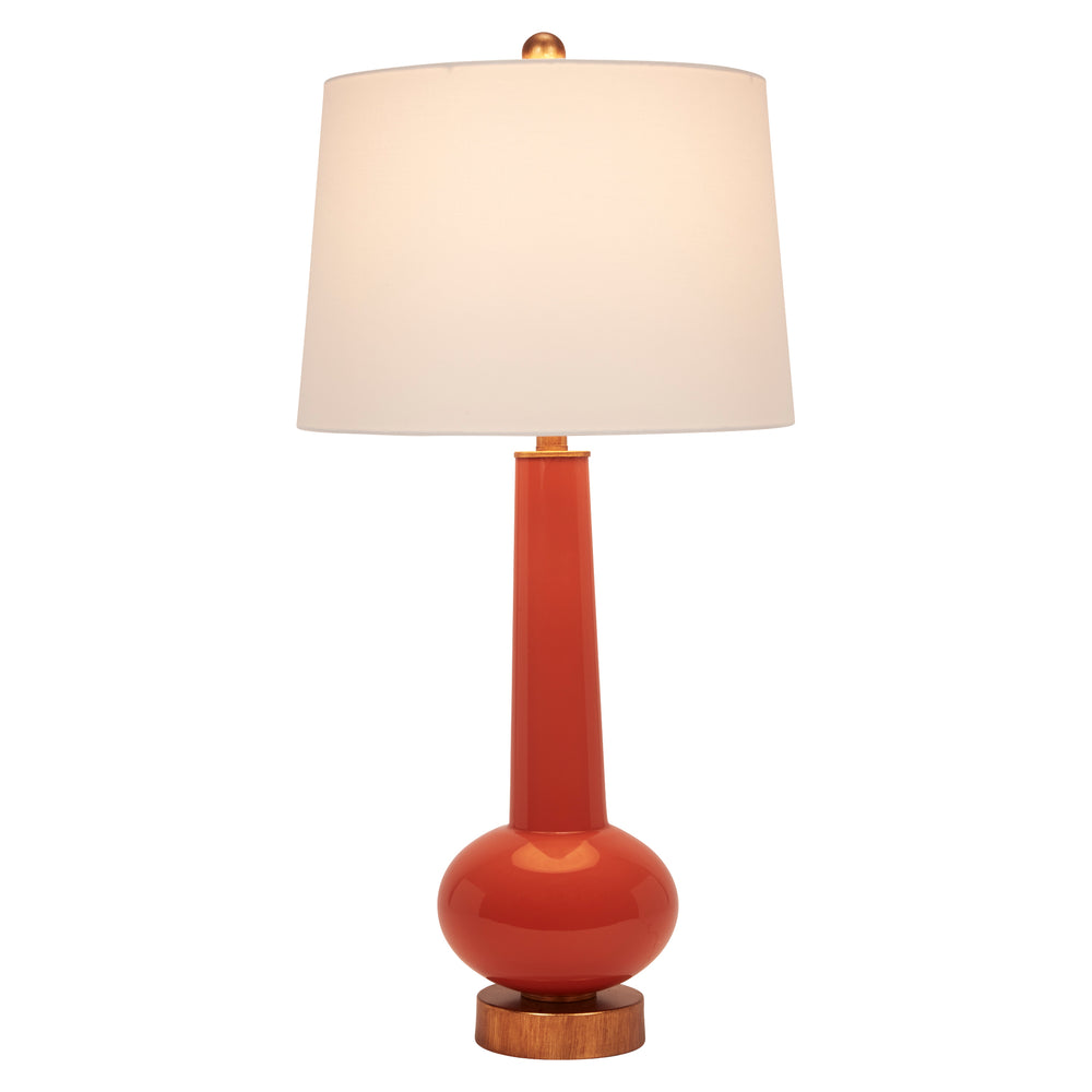 Orange table lamp with white linen shade, brass fittings, and round wooden base.