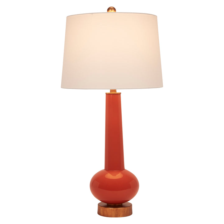 Orange table lamp with white linen shade, brass fittings, and round wooden base.