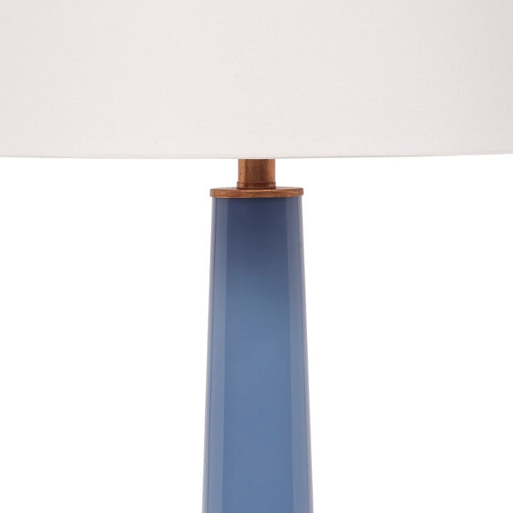 Blue ceramic lamp stem with brass collar under a white linen drum shade