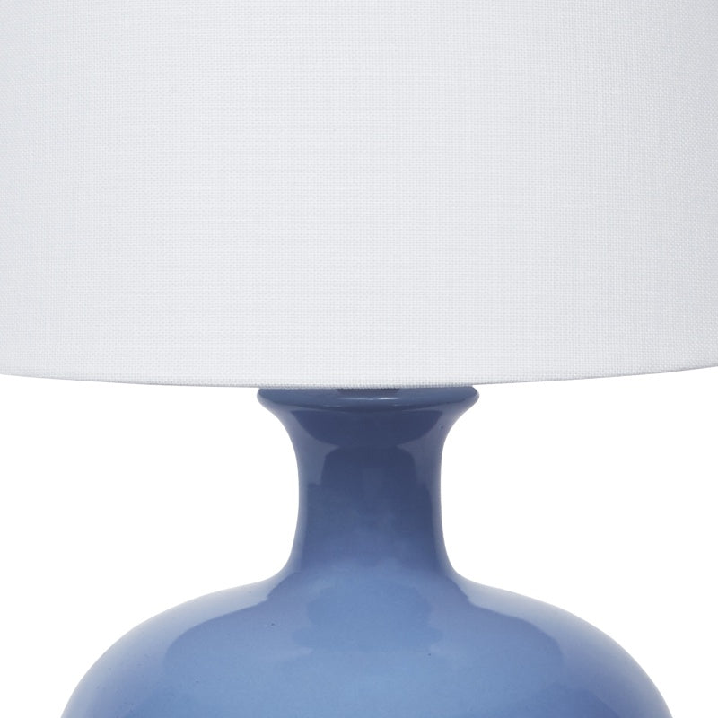 Dark blue ceramic lamp body with brass neck and white linen shade