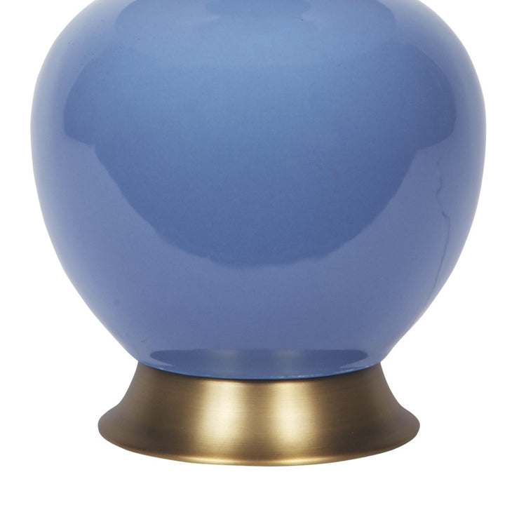 Dark blue ceramic table lamp with white linen shade and brass base