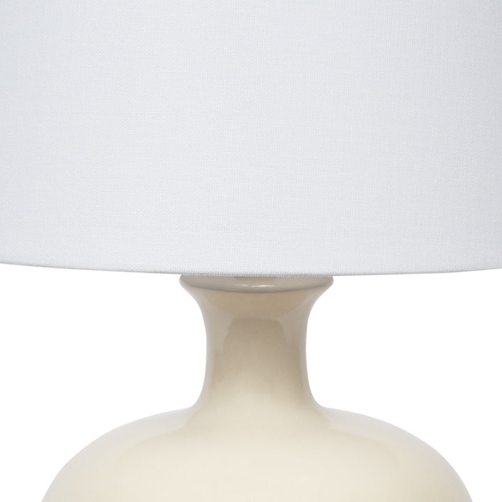 Cream ceramic table lamp body with flared neck under white linen shade