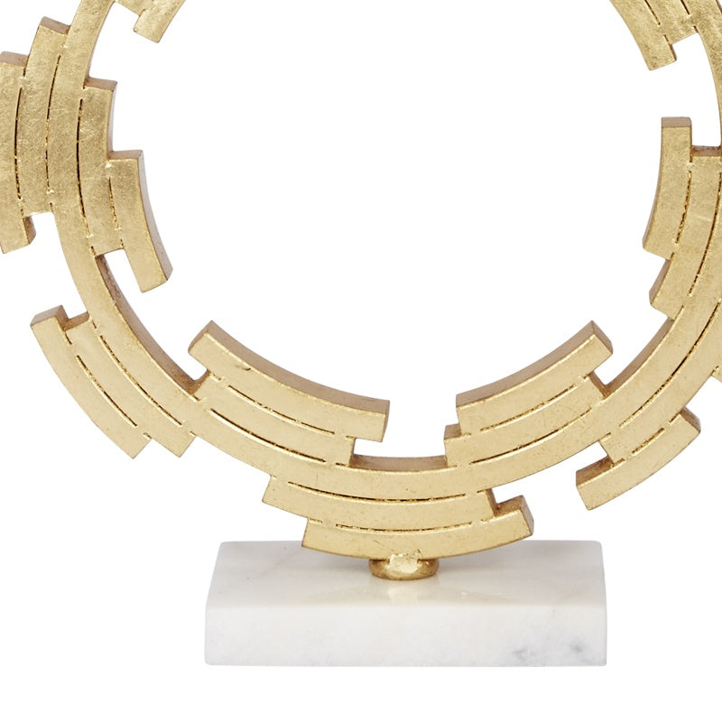 Gold metal table lamp base with circular ring sculpture on white pedestal